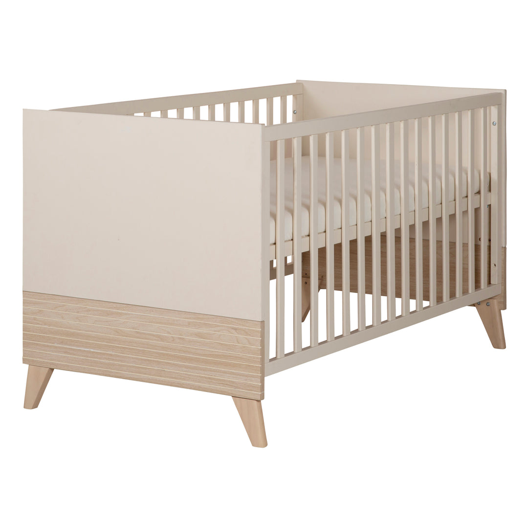 Babybett 'Sidney' in Cashmere/Eiche mit Gitterstäben und Matratze, freigestellte Ansicht schräg von vorne