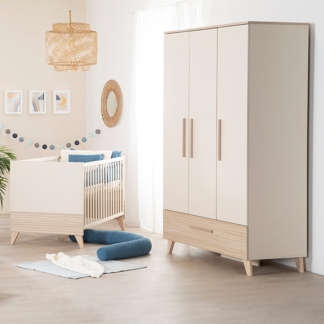 Babyzimmer 'Sidney' mit Kleiderschrank und Babybett, Rattan-Hängelampe und blauer Dekokissenrolle