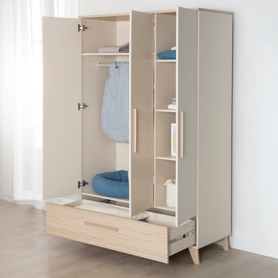 Geöffneter Kleiderschrank 'Sidney' im Zimmer mit Kleiderstange, Ablagefächern und ausgezogener Schublade