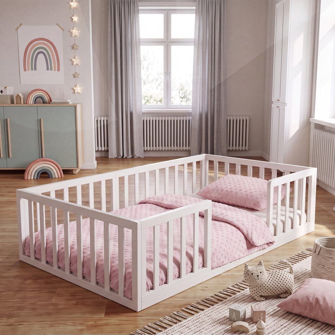 Lit bas Montessori laqué blanc dans une chambre d'enfant avec affiche arc-en-ciel, guirlande lumineuse en forme d'étoiles et linge de lit rose. Entièrement généré par IA