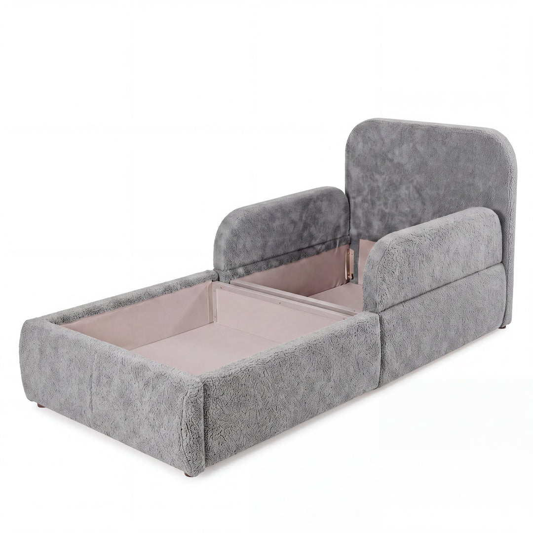 Cama infantil gris de bouclé abierta con el arcón de almacenaje visible, imagen recortada.