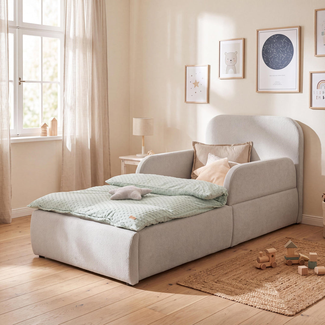 Cama infantil gris claro de bouclé con protección anticaídas y galería de cuadros en una habitación infantil. Generada íntegramente con IA.