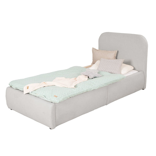 Cama infantil gris claro de bouclé con protección anticaídas y ropa de cama color menta, imagen recortada.