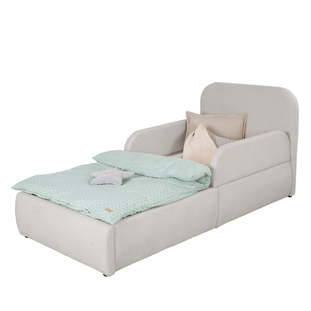 Cama infantil gris claro de bouclé con protección anticaídas, cabecero y ropa de cama color menta, imagen recortada.