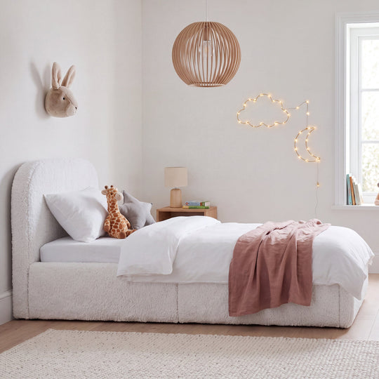 Cama infantil blanca de bouclé con peluches, lámpara colgante y guirnalda de luces de nubes y luna en la habitación. Generada íntegramente con IA.