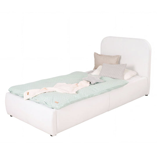 Cama infantil blanca de bouclé con protección anticaídas y ropa de cama color menta, imagen recortada.