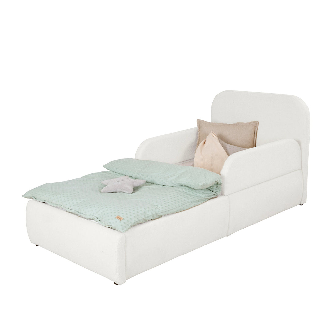 Cama infantil blanca de bouclé con protección anticaídas, cabecero y ropa de cama color menta, imagen recortada.