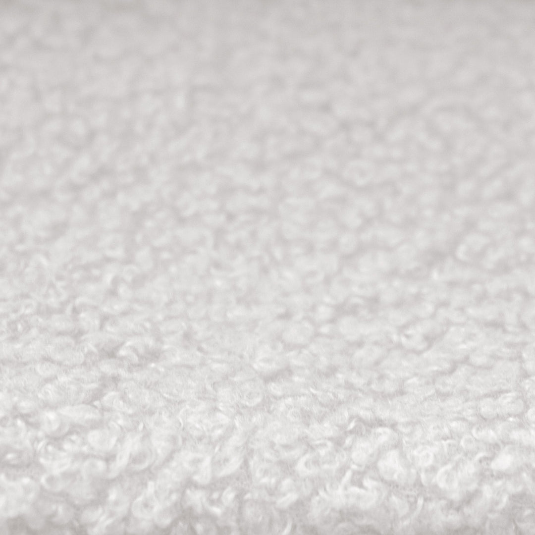 Primer plano de la funda de tela bouclé blanca y texturizada de la cama infantil.