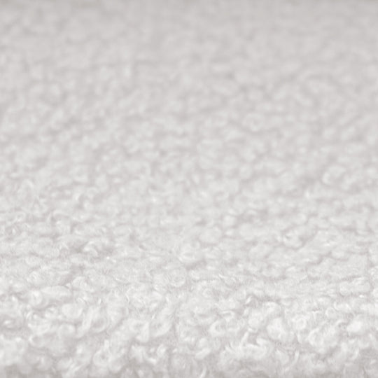 Primer plano de la funda de tela bouclé blanca y texturizada de la cama infantil.