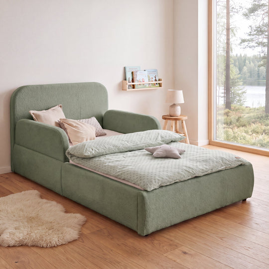 Green roba Little Dream children's bed in a children's room with lake view, bookshelf and sheepskin rug. Fully AI-generated.