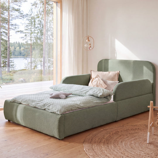 Green roba Little Dream children's bed in a children's room with lake view and a hanging mobile above the bed. Fully AI-generated.