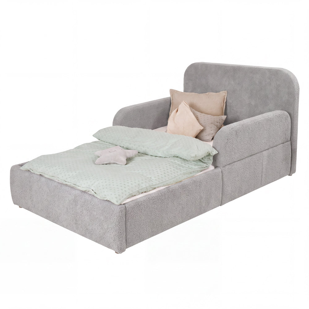 Cama infantil roba Little Dream gris claro con cabecero y protecciones laterales, vestida con ropa de cama y cojines. Generada parcialmente con IA.