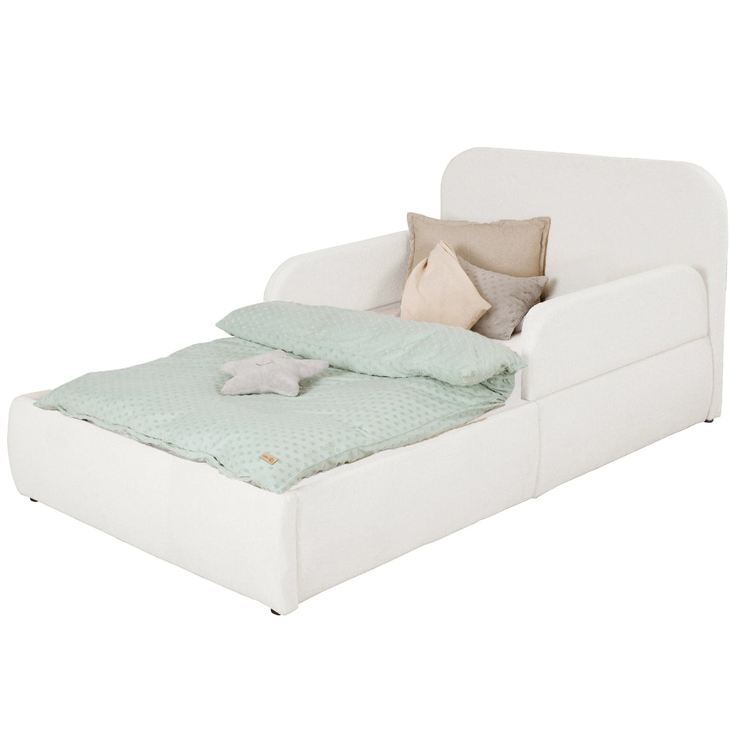 Cama blanca de bouclé con cabecero y piecero, ropa de cama color menta, imagen recortada.