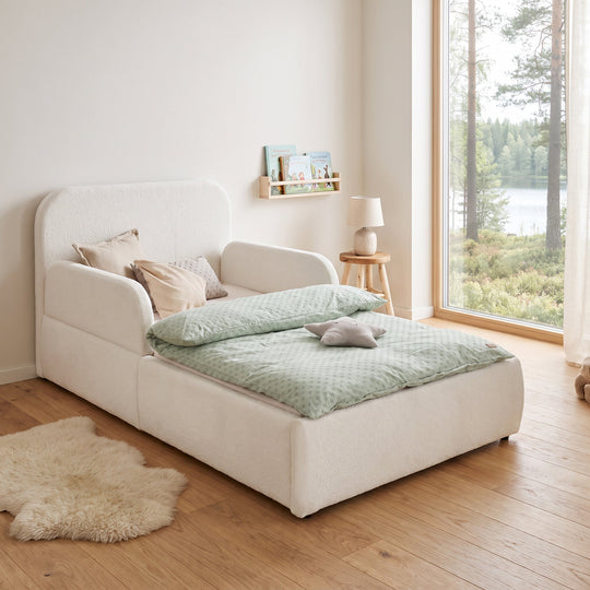 White bouclé bed with bedside lamp, bookshelf and lake view in the room. Fully AI-generated.