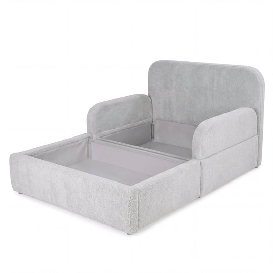 Cama infantil roba Little Dream gris claro con el arcón abierto y espacio de almacenaje bajo la superficie de descanso. Generada parcialmente con IA.