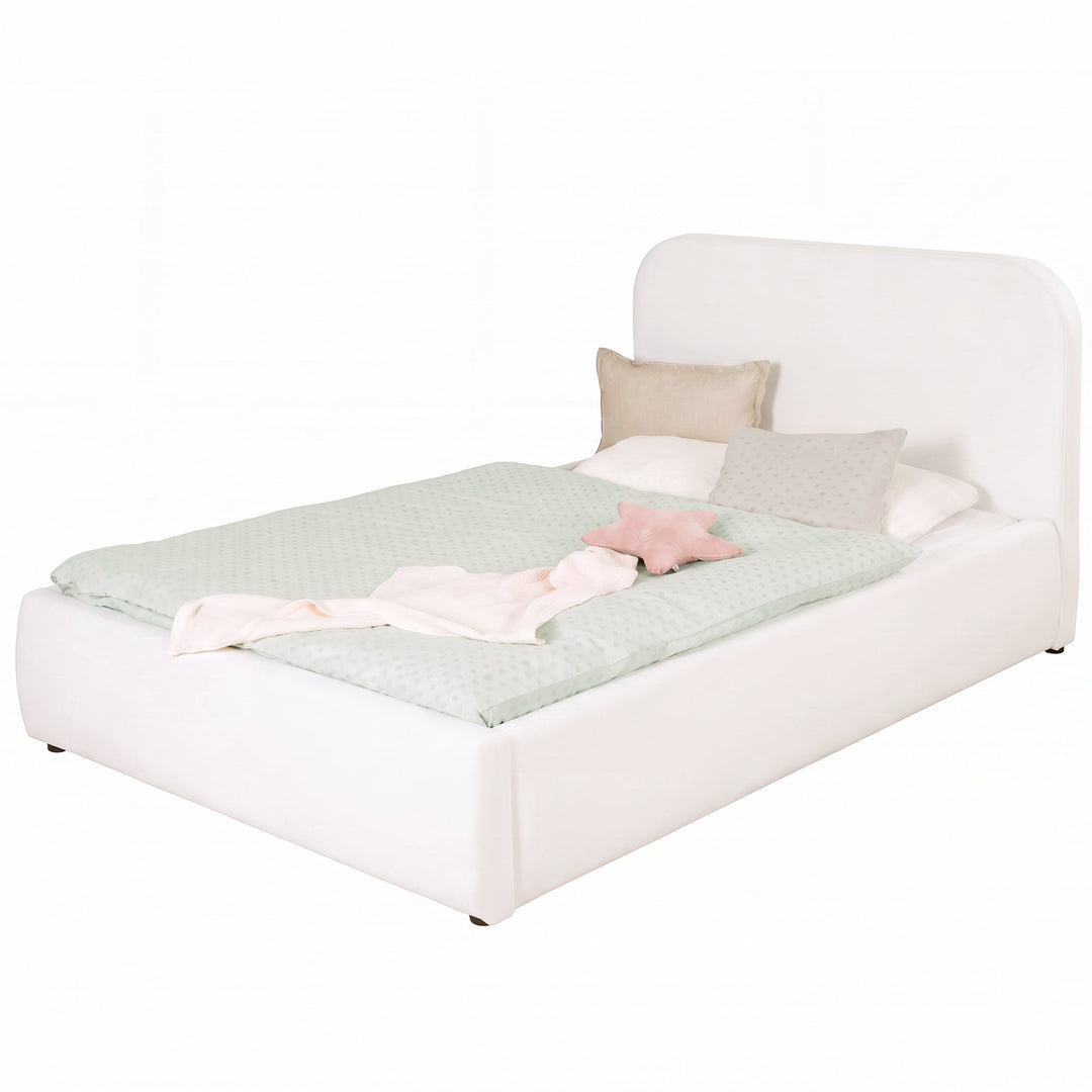 Cama infantil roba Little Dream blanca con cabecero tapizado, vestida con ropa de cama de lunares y cojines. Generada parcialmente con IA.