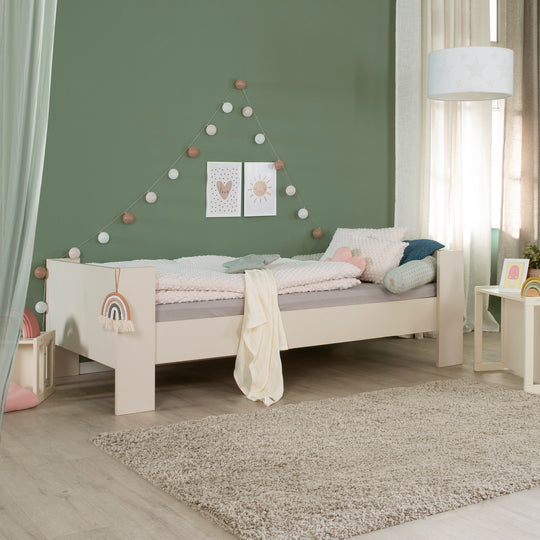 Einzelbett 90 x 200 cm 'Flexi Grow' in Cashmere im Kinderzimmer mit grüner Wand, Regenbogen-Applikation am Bettrahmen und Dekoration